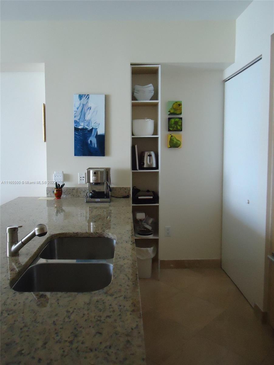 A kitchen features a granite countertop, a double sink, and a tall built-in shelving unit — 1830 S Ocean Dr # 1505, Hallandale Beach FL 33009, HALLANDALE BEACH, FL