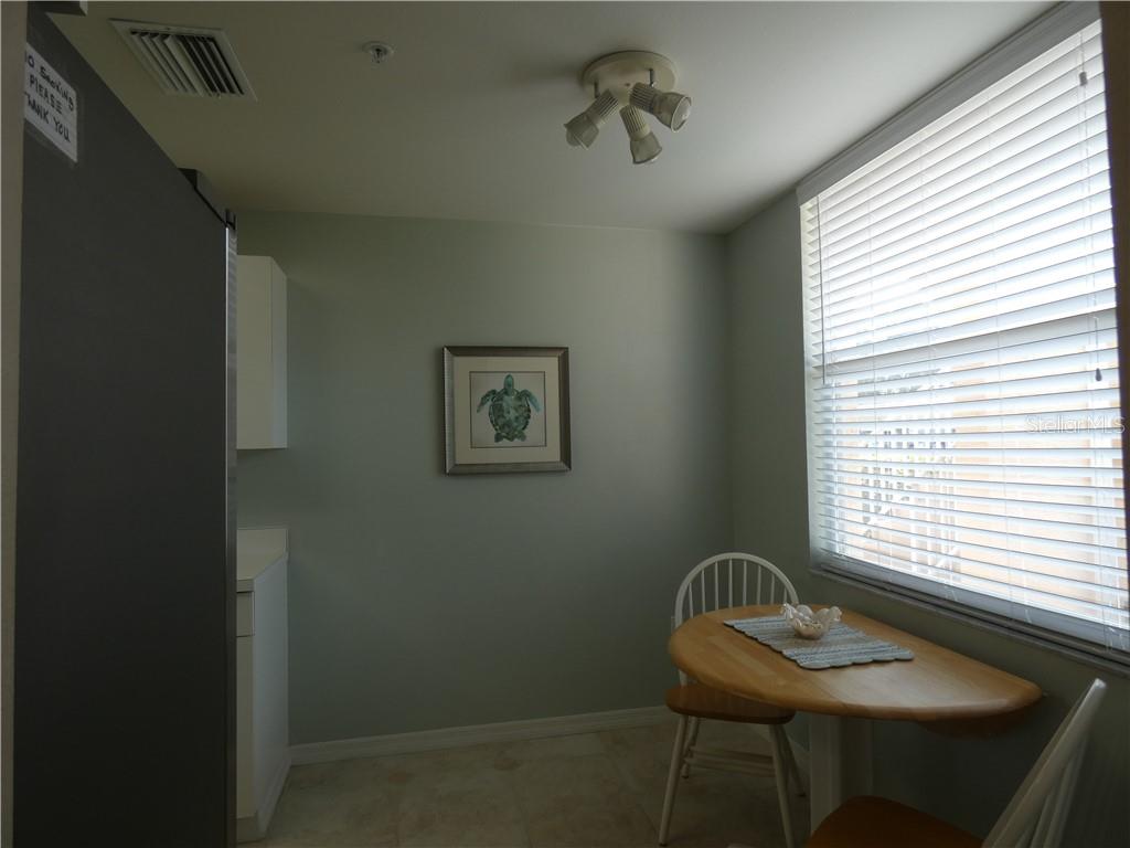 A small dining area features a round wooden table, white chairs, and a turtle wall print — 8735 OLDE HICKORY AVENUE UNIT 8101, SARASOTA, FL