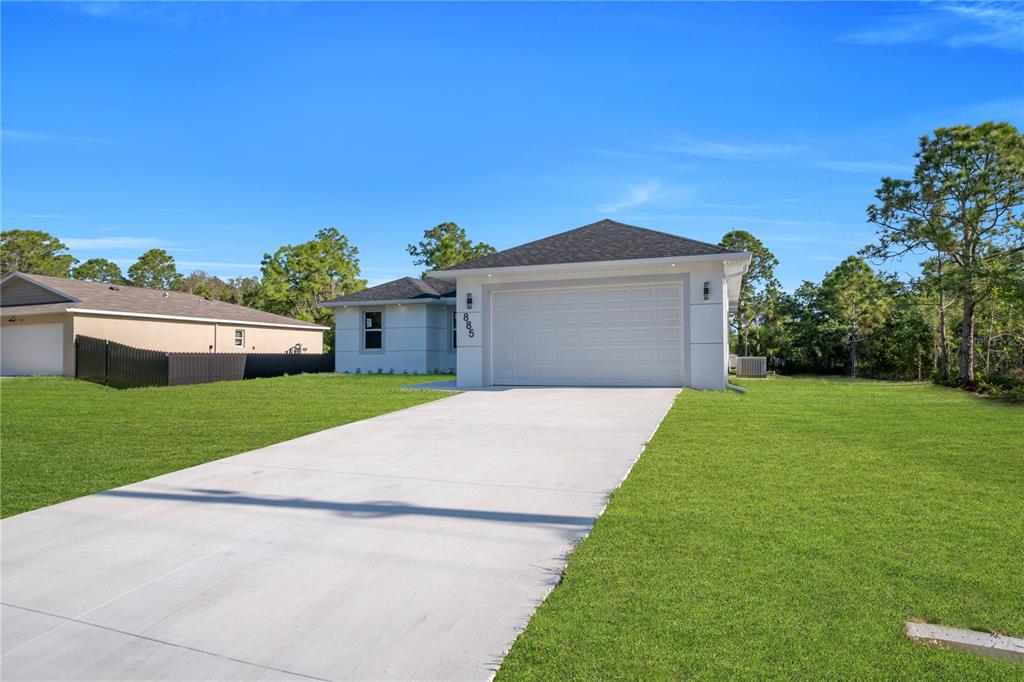 A modern single-story house with a white exterior, a two-car garage, and a concrete driveway — 885 BARCIA STREET E, LEHIGH ACRES, FL