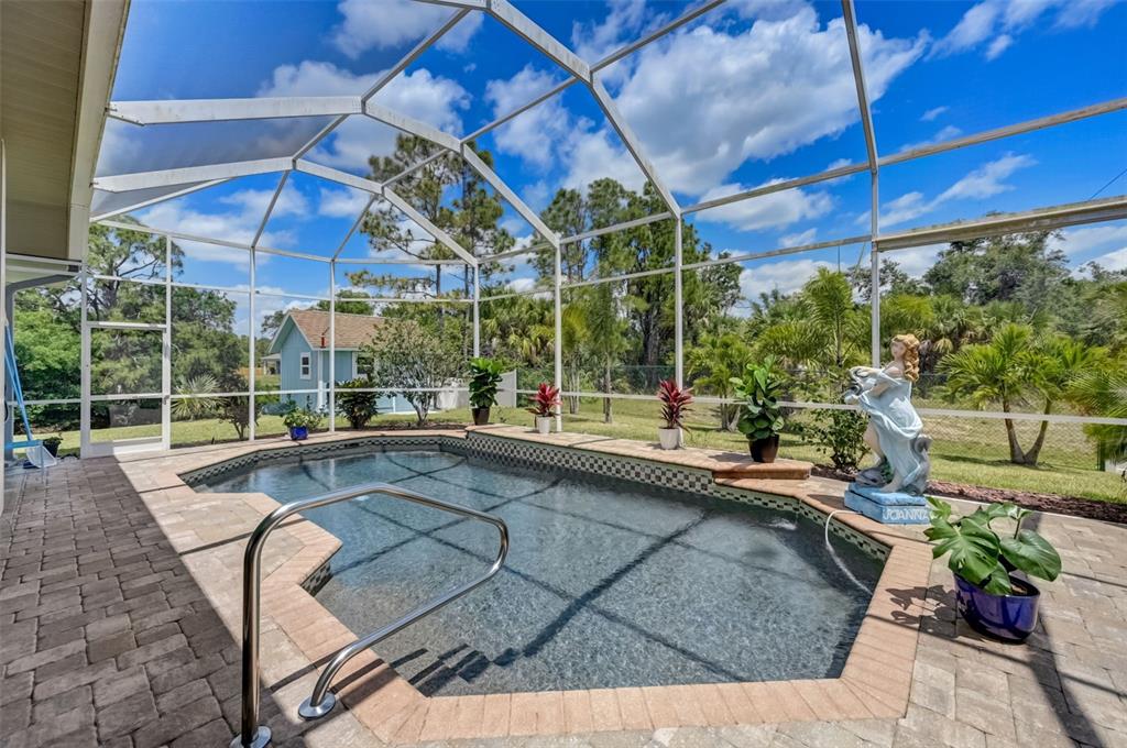 A screened-in swimming pool with a stone deck and a decorative statue on the patio — 2459 JOHANNESBERG ROAD, NORTH PORT, FL