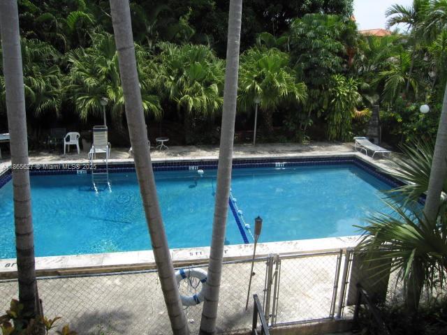 An outdoor swimming pool is surrounded by palm trees and a chain-link fence — 645 NE 77th St # 6, Miami FL 33138, MIAMI, FL