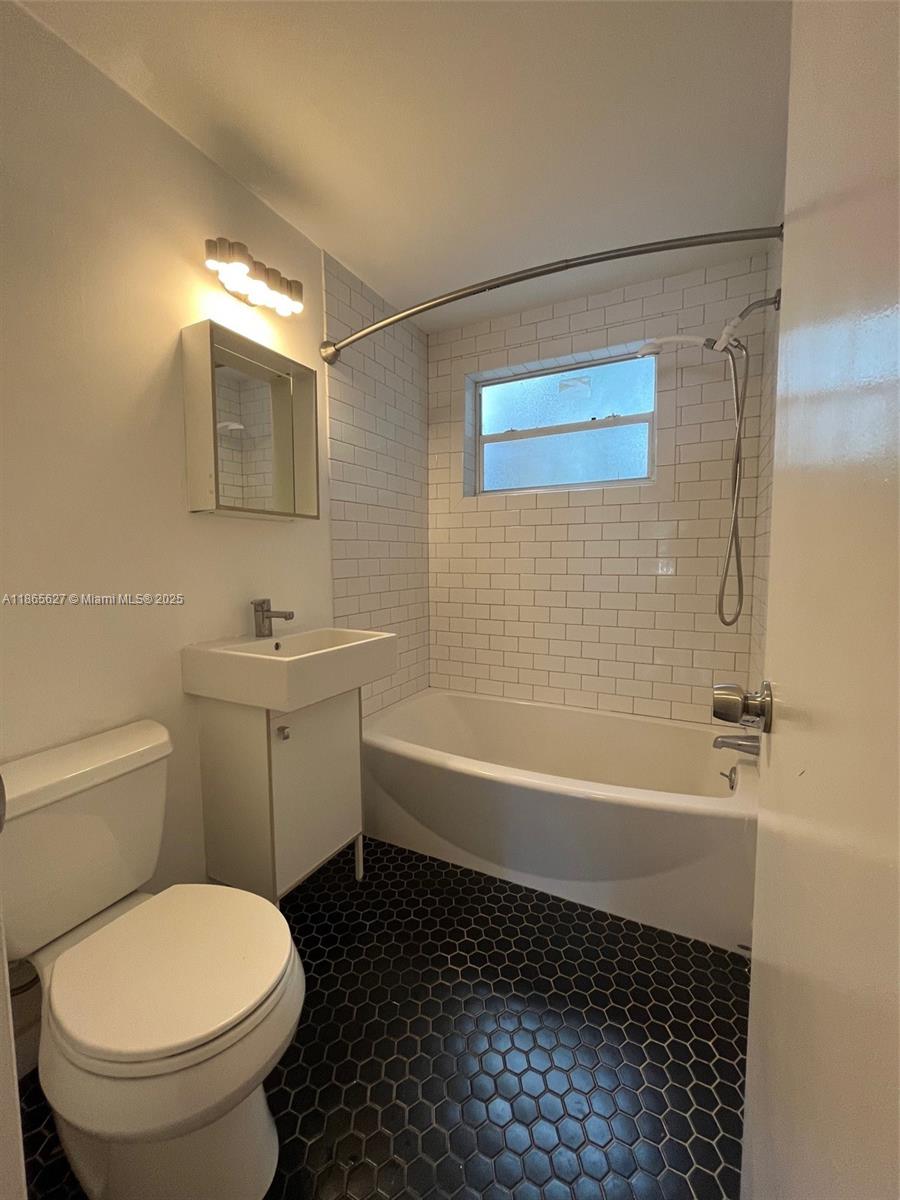 A bathroom features a white pedestal sink, a toilet, and a tub with subway tile — 645 NE 77th St # 6, Miami FL 33138, MIAMI, FL