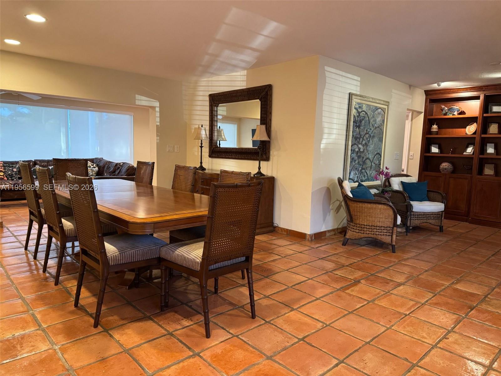 A dining room features a wooden table, wicker chairs, and terracotta tile flooring — 1110 Redbird Ave, Miami Springs FL 33166, MIAMI SPRINGS, FL