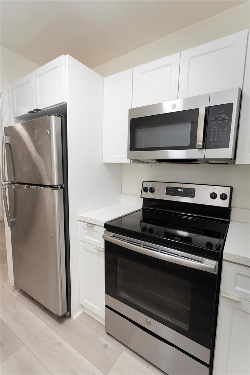 A kitchen features white cabinets, stainless steel appliances, and light-colored flooring — 111 SW 31st Ct, Miami FL 33135, MIAMI, FL
