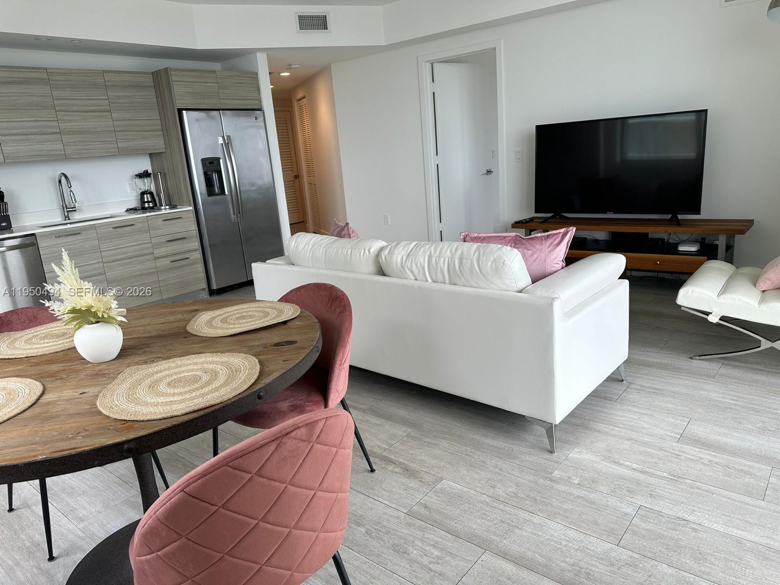 An open-concept living area features a kitchen with wood-grain cabinets, a dining table, and sofa — 121 NE 34th St # 2309, Miami FL 33137, MIAMI, FL
