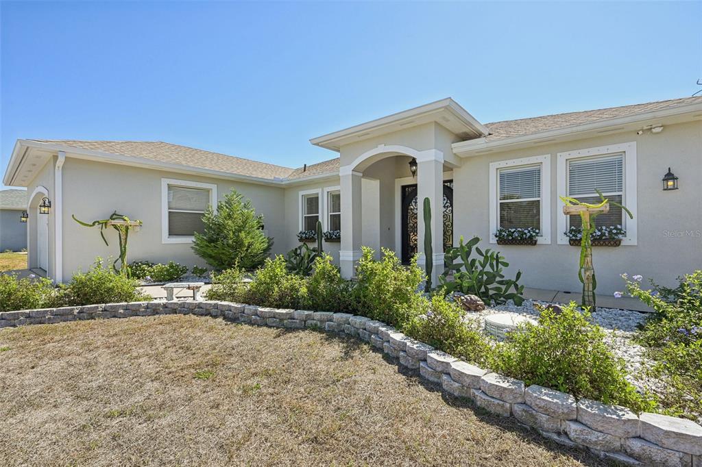 A single-story house with a beige exterior, a stone-bordered garden, and a covered front entrance — 13359 TOLMAN AVENUE, PORT CHARLOTTE, FL