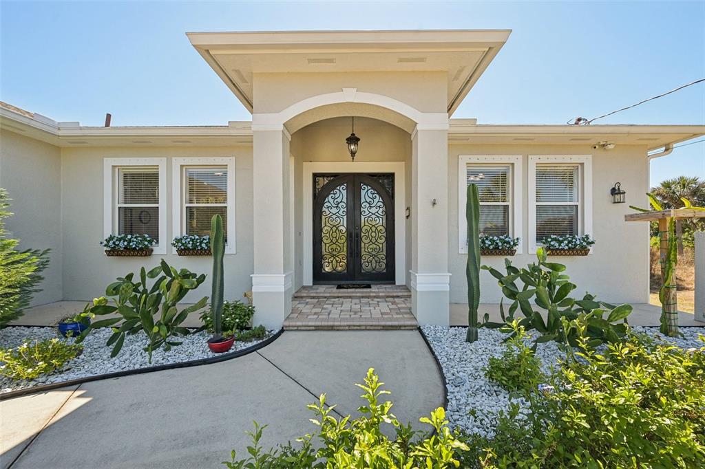 The exterior of a single-story house features a double front door and desert-style landscaping — 13359 TOLMAN AVENUE, PORT CHARLOTTE, FL
