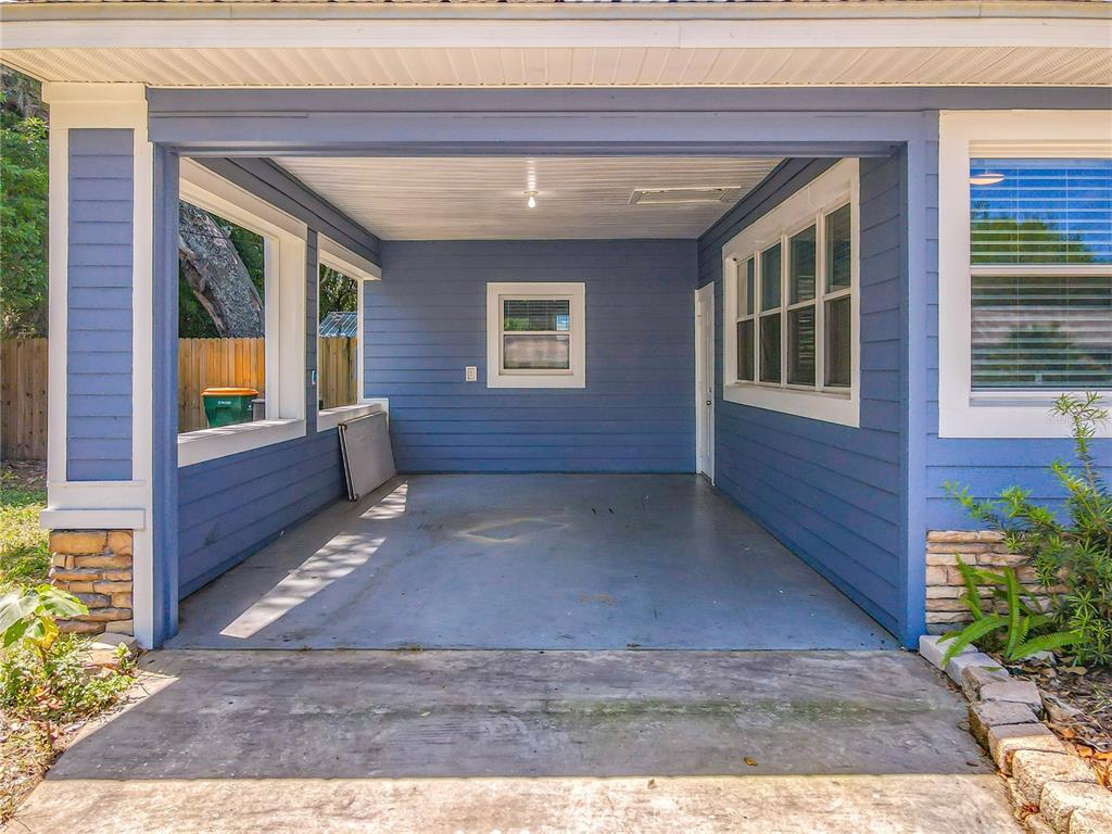 A blue-sided carport features a concrete floor, a ceiling light, and windows on both sides — 1006 E 11TH AVENUE, MOUNT DORA, FL