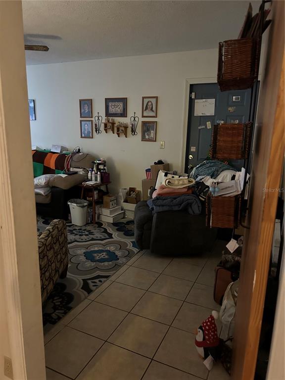 A living room features tiled floors, a patterned area rug, and a dark recliner chair — 5405 1ST STREET NE, ST PETERSBURG, FL