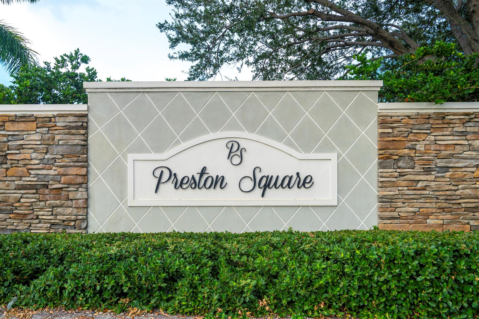 A stone and stucco monument sign for Preston Square sits behind a manicured green hedge — PALM SPRINGS, FL