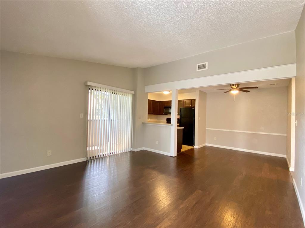 An open-concept living and dining area features dark wood flooring and a kitchen with cabinets — 2942 ANTIQUE OAKS CIRCLE UNIT 88, WINTER PARK, FL