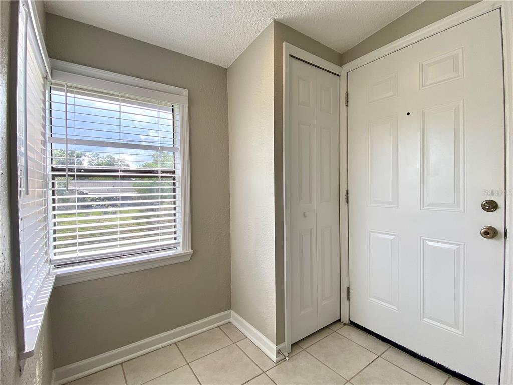 An entryway features light-colored tile flooring, a white front door, and a window with blinds — 2942 ANTIQUE OAKS CIRCLE UNIT 88, WINTER PARK, FL
