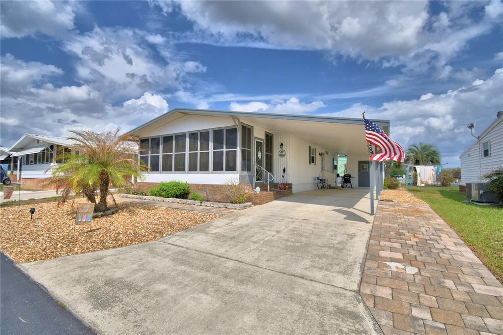A single-story manufactured home with a screened-in porch, carport, and paved driveway — 4918 ROSEWOOD STREET, WINTER HAVEN, FL
