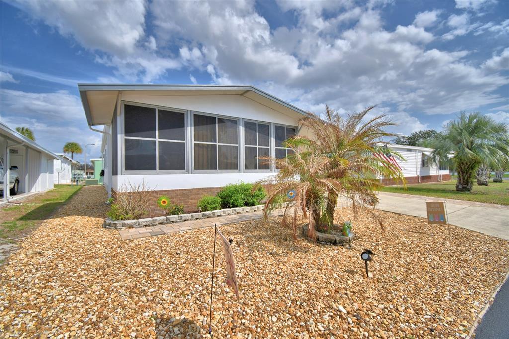 A single-story manufactured home with a screened-in porch and a gravel front yard — 4918 ROSEWOOD STREET, WINTER HAVEN, FL