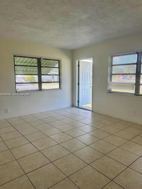 An empty room features light-colored tile flooring, two windows with blinds, and a white door — 5649 SW 27th St # 1, West Park FL 33023, WEST PARK, FL