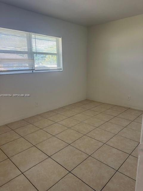 An empty room features light-colored floor tiles, white walls, and a window with blinds — 5649 SW 27th St # 1, West Park FL 33023, WEST PARK, FL