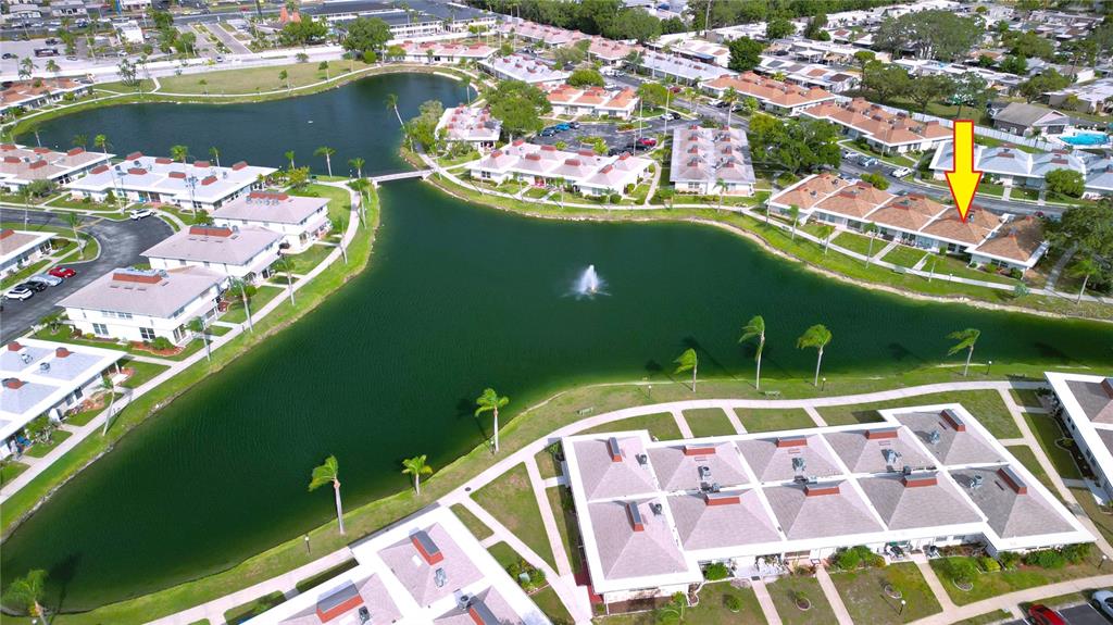 An aerial view shows a residential community with multiple buildings surrounding a central lake — 4324 TAHITIAN GARDENS CIRCLE UNIT J, HOLIDAY, FL