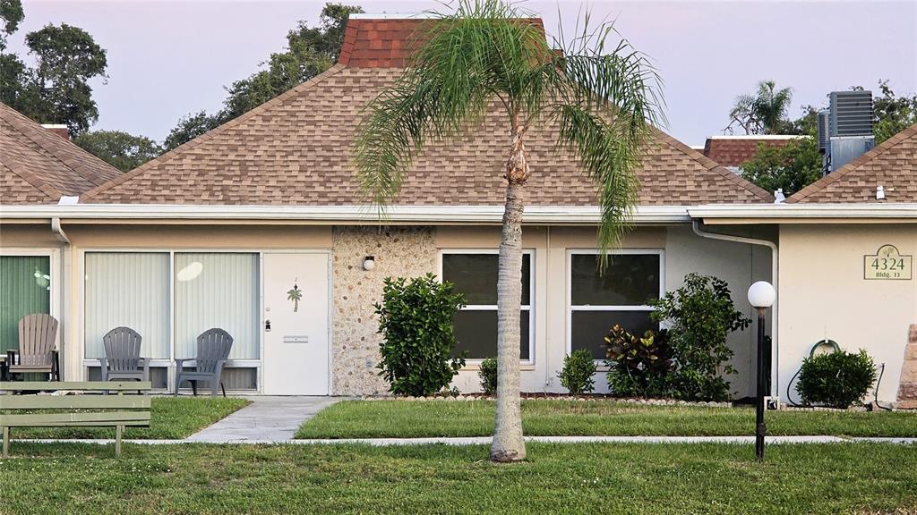 A single-story residential building with a brown shingled roof, a palm tree, and a bench — 4324 TAHITIAN GARDENS CIRCLE UNIT J, HOLIDAY, FL