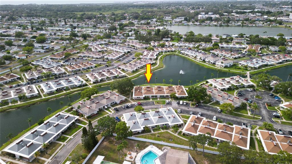 An aerial view shows a residential complex with multiple buildings surrounding a central pond — 4324 TAHITIAN GARDENS CIRCLE UNIT J, HOLIDAY, FL