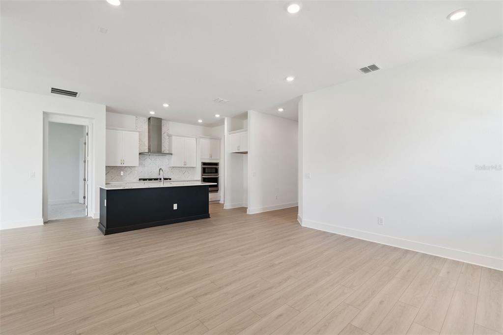 A kitchen with a dark island and white cabinets opens to a spacious living area — 17412 HONEYBELL TANGELO COURT, WINTER GARDEN, FL