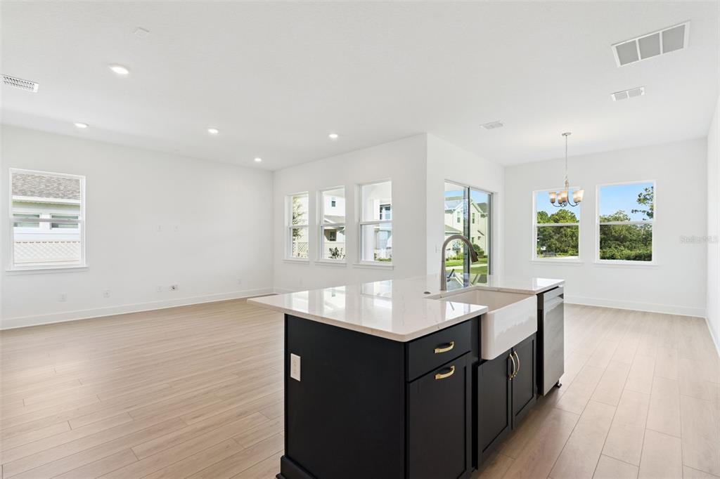 A kitchen island with a farmhouse sink sits in an open-concept room with light flooring — 17412 HONEYBELL TANGELO COURT, WINTER GARDEN, FL