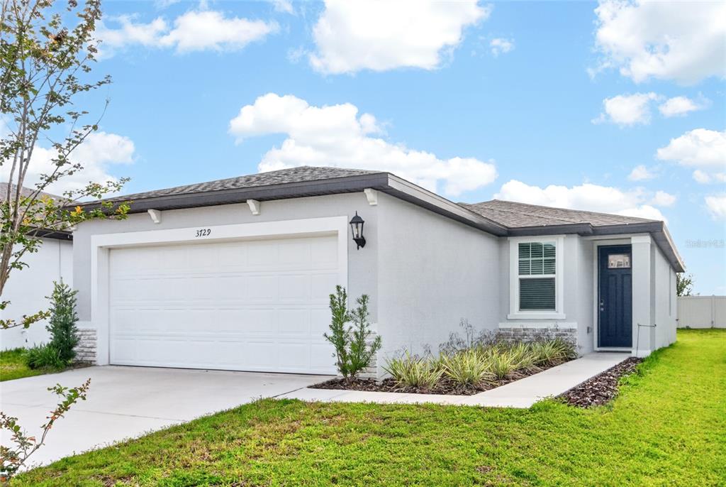 A single-story house with a white garage, gray stucco exterior, and a dark blue door — 3729 RADIANT MOUNTAIN DRIVE, PLANT CITY, FL