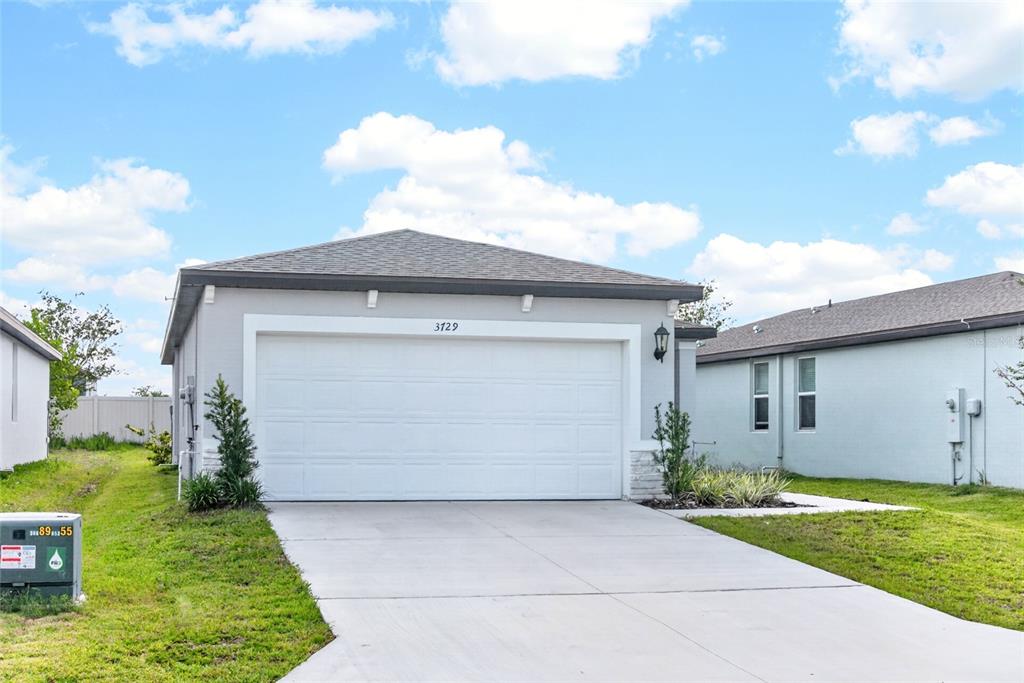 A single-story house with a white garage door, gray siding, and a concrete driveway — 3729 RADIANT MOUNTAIN DRIVE, PLANT CITY, FL