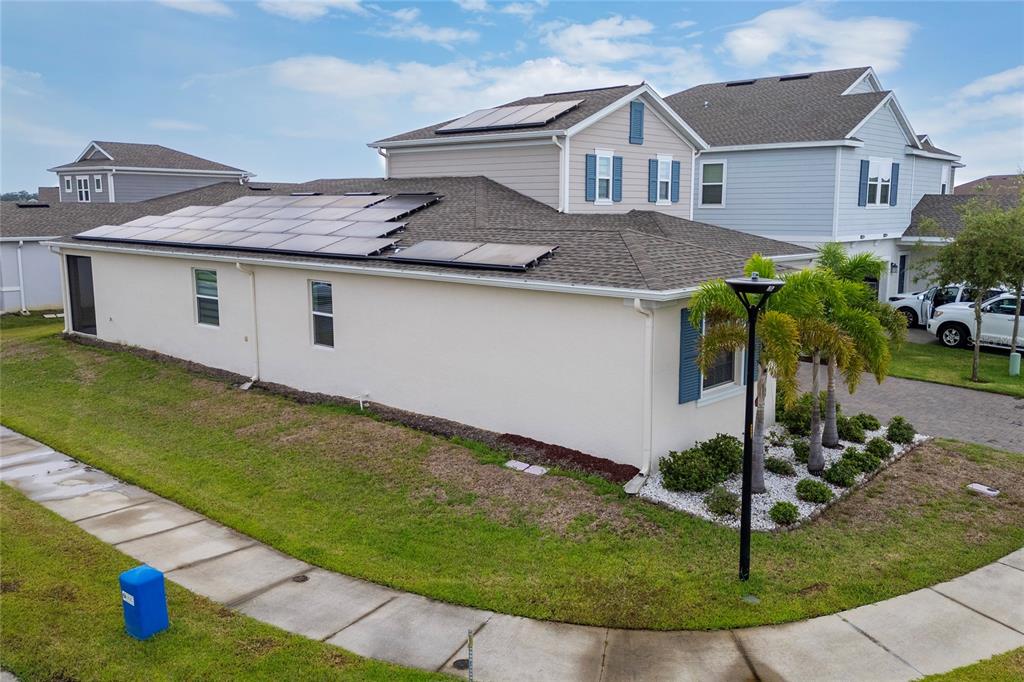 An exterior view of a two-story house featuring rooftop solar panels and a side driveway — 1839 GOOD NEIGHBOR LOOP, KISSIMMEE, FL