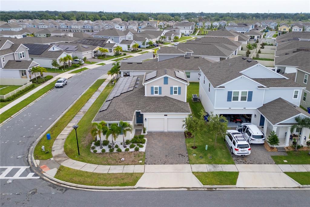 An aerial view shows suburban houses with paved driveways, solar panels, and manicured lawns — 1839 GOOD NEIGHBOR LOOP, KISSIMMEE, FL