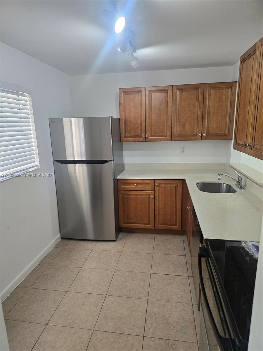 A kitchen features wood cabinets, stainless steel appliances, and light-colored countertops — 8045 SW 107th Ave # 323, Miami FL 33173, MIAMI, FL