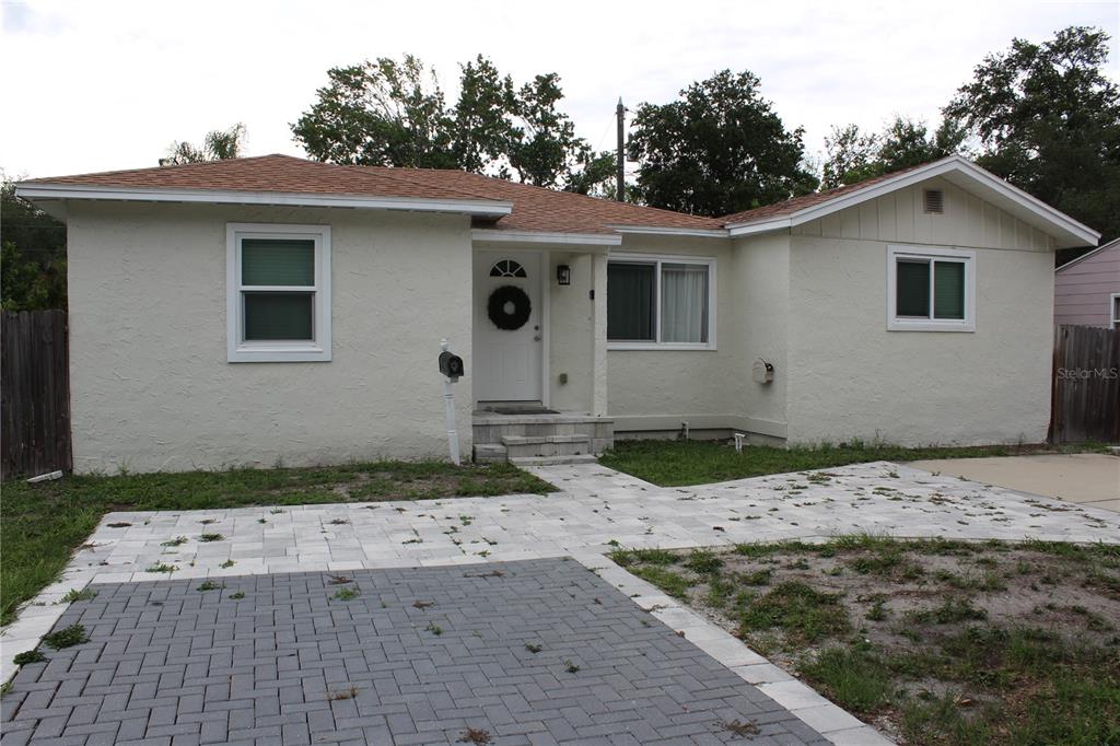 A single-story house with a light-colored stucco exterior, a paved driveway, and a front walkway — 6014 CEDAR STREET NE, ST PETERSBURG, FL
