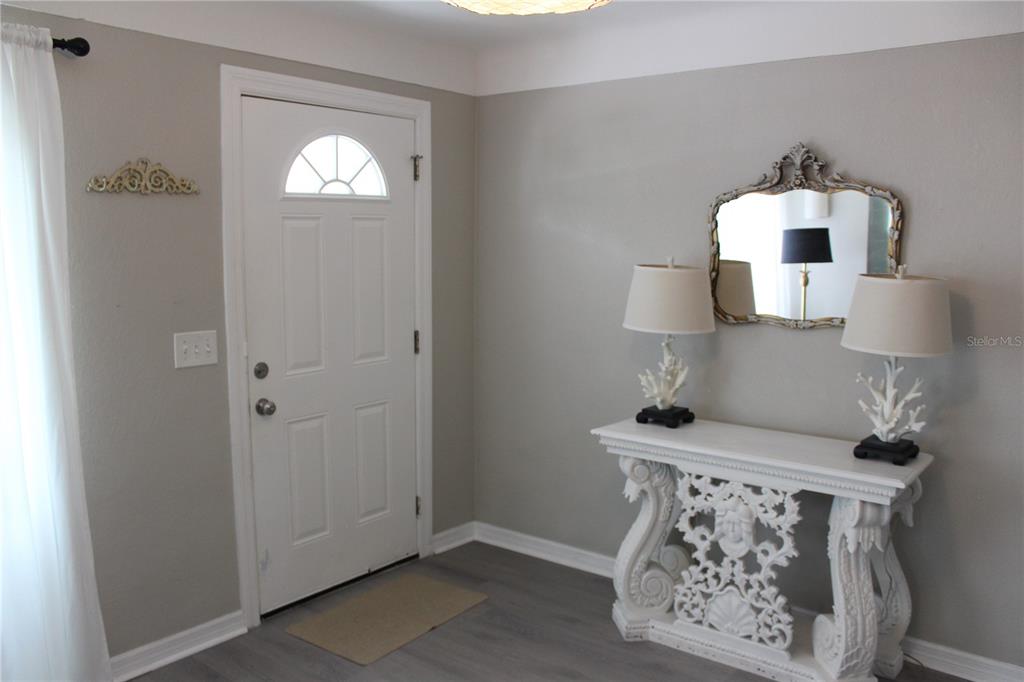 An entryway features a white door, a decorative console table, two lamps, and a mirror — 6014 CEDAR STREET NE, ST PETERSBURG, FL