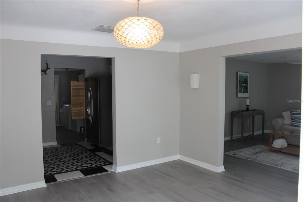 A room with gray walls, light wood-look flooring, a textured pendant light, and two doorways — 6014 CEDAR STREET NE, ST PETERSBURG, FL
