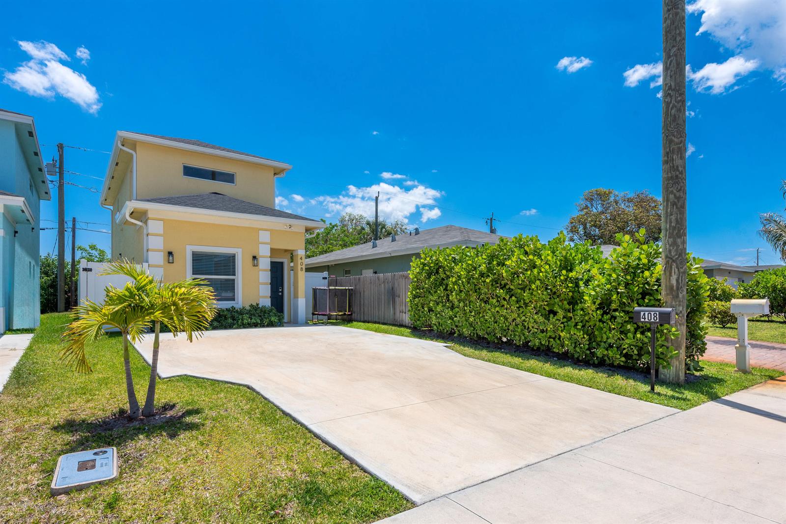A yellow two-story house features a concrete driveway, a palm tree, and a hedge — 408 NW 12th Avenue, Boynton Beach FL 33435, BOYNTON BEACH, FL