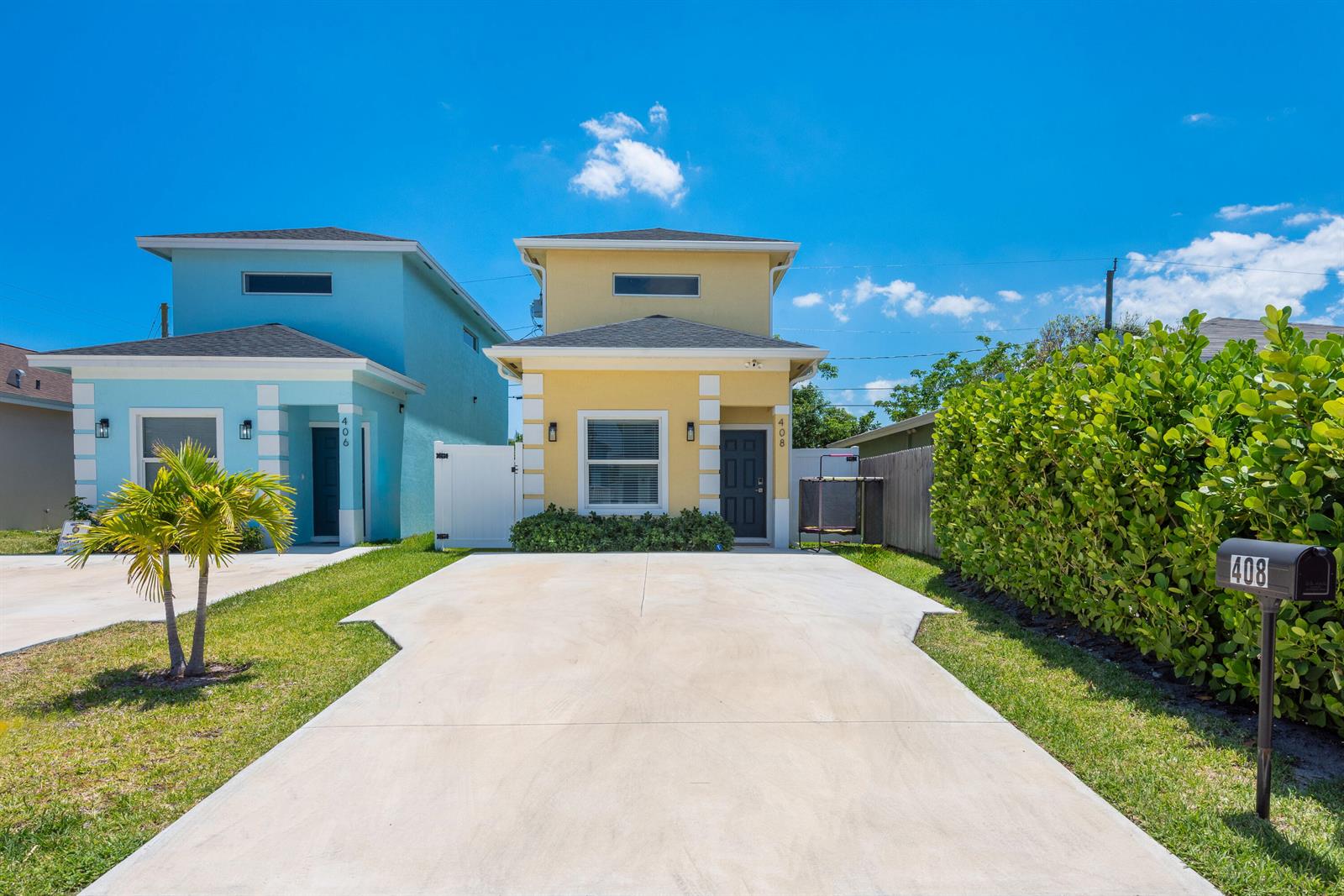 A yellow two-story house with a concrete driveway and a green hedge on the right — 408 NW 12th Avenue, Boynton Beach FL 33435, BOYNTON BEACH, FL