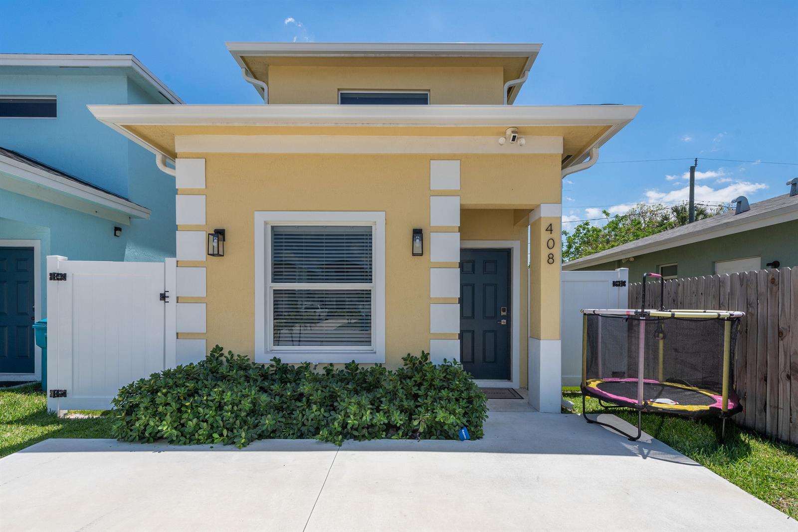 A yellow single-story house features a front window, a dark door, and a small trampoline — 408 NW 12th Avenue, Boynton Beach FL 33435, BOYNTON BEACH, FL