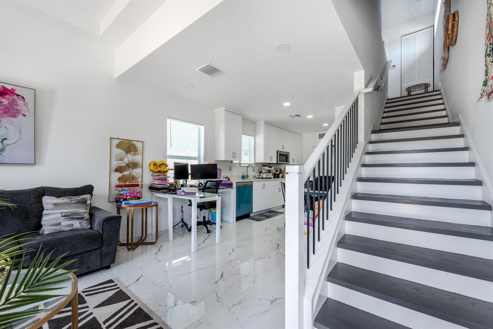 A living area with a desk, kitchen, and staircase with dark treads and white risers — 408 NW 12th Avenue, Boynton Beach FL 33435, BOYNTON BEACH, FL