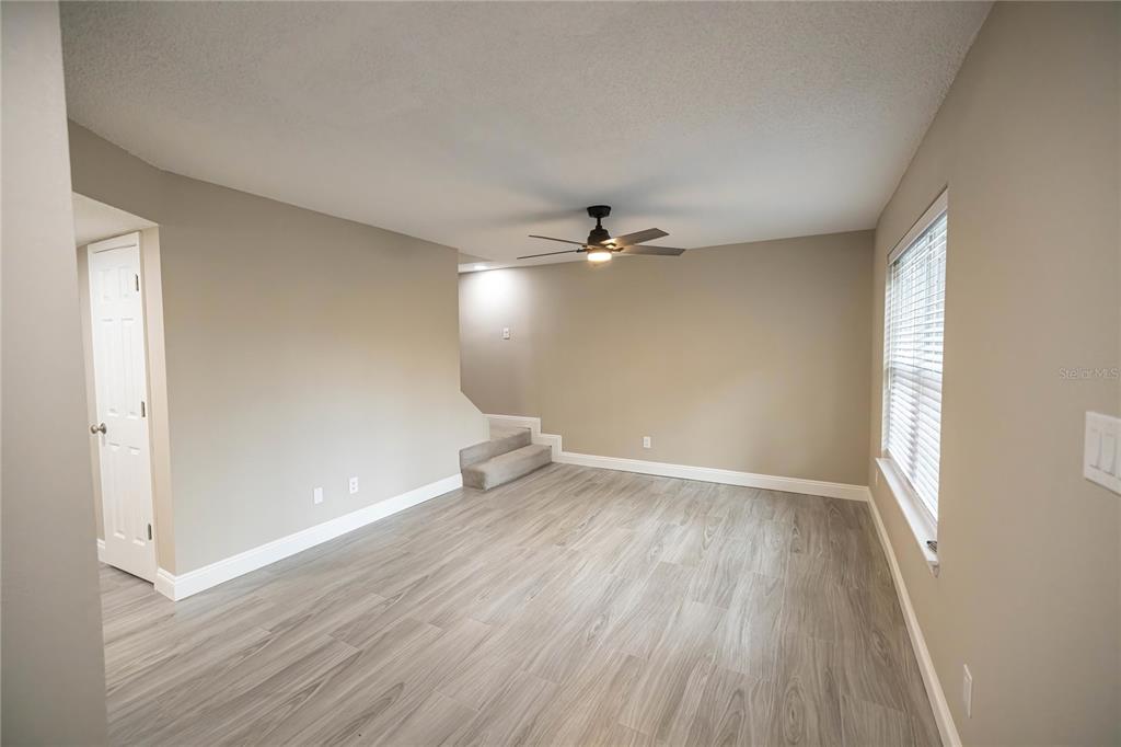 An empty room with light gray wood-look flooring, beige walls, and a ceiling fan — 740 N FAIRFIELD DRIVE, PENSACOLA, FL