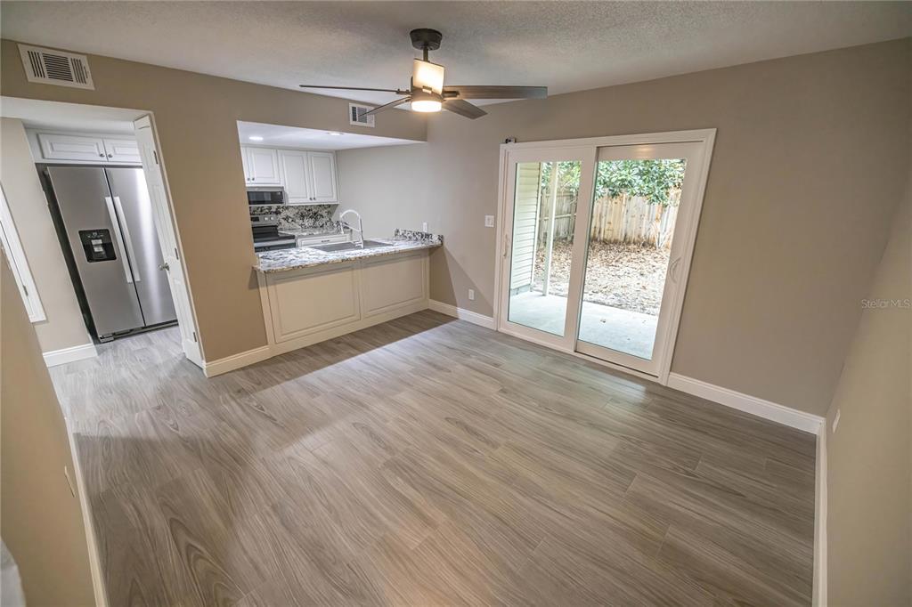 A dining area with wood-look flooring features a breakfast bar, kitchen access, and sliding doors — 740 N FAIRFIELD DRIVE, PENSACOLA, FL