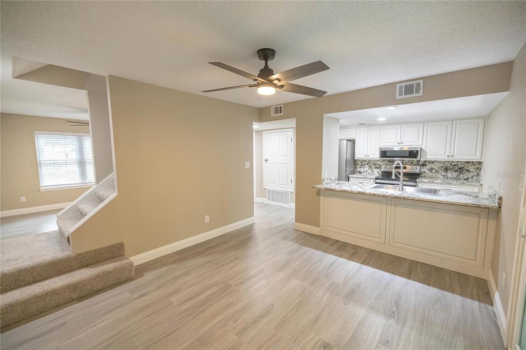 A dining area with wood-look flooring leads to a kitchen with white cabinets and granite countertops — 740 N FAIRFIELD DRIVE, PENSACOLA, FL
