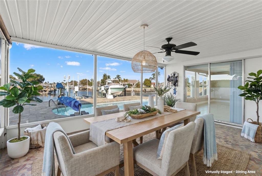 A dining area with a wooden table and chairs overlooks a pool and boat dock — 3939 RUDDER WAY, NEW PORT RICHEY, FL