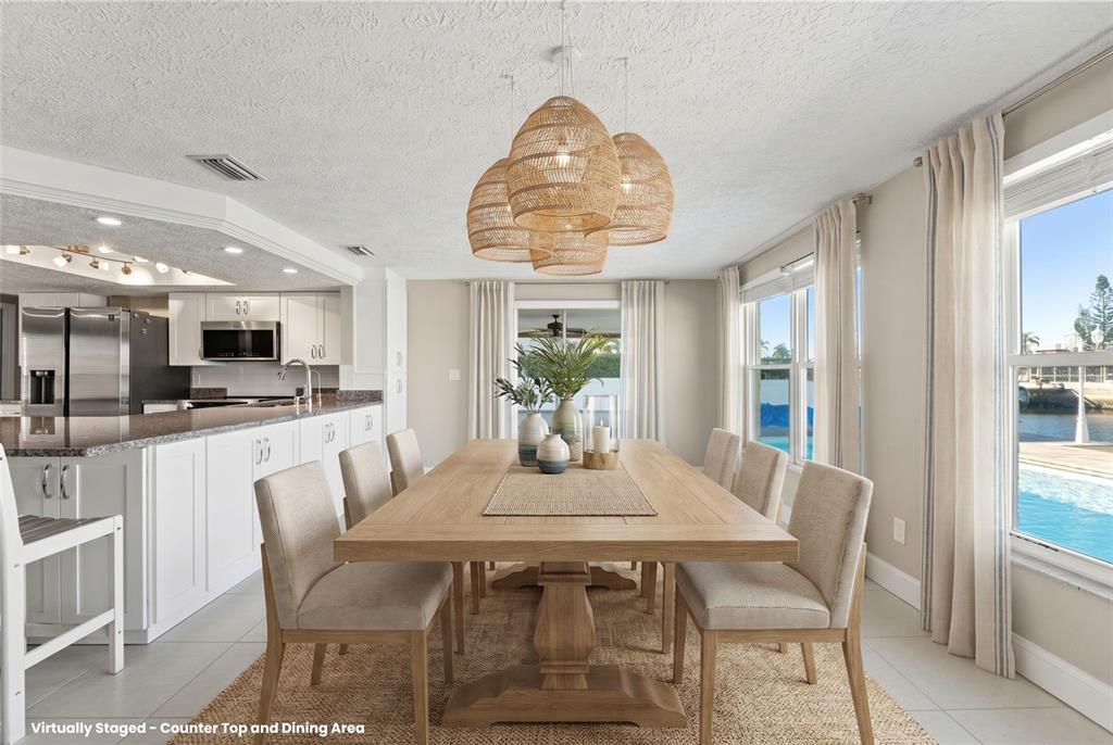 A dining area with a wooden table, woven pendant lights, and a view of a pool — 3939 RUDDER WAY, NEW PORT RICHEY, FL