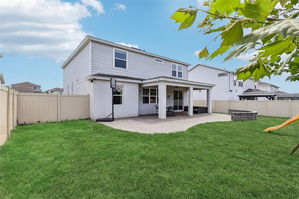 The backyard features a paved patio, a basketball hoop, a grassy lawn, and vinyl fencing — 2575 AUBURN RIDGE DRIVE, APOPKA, FL