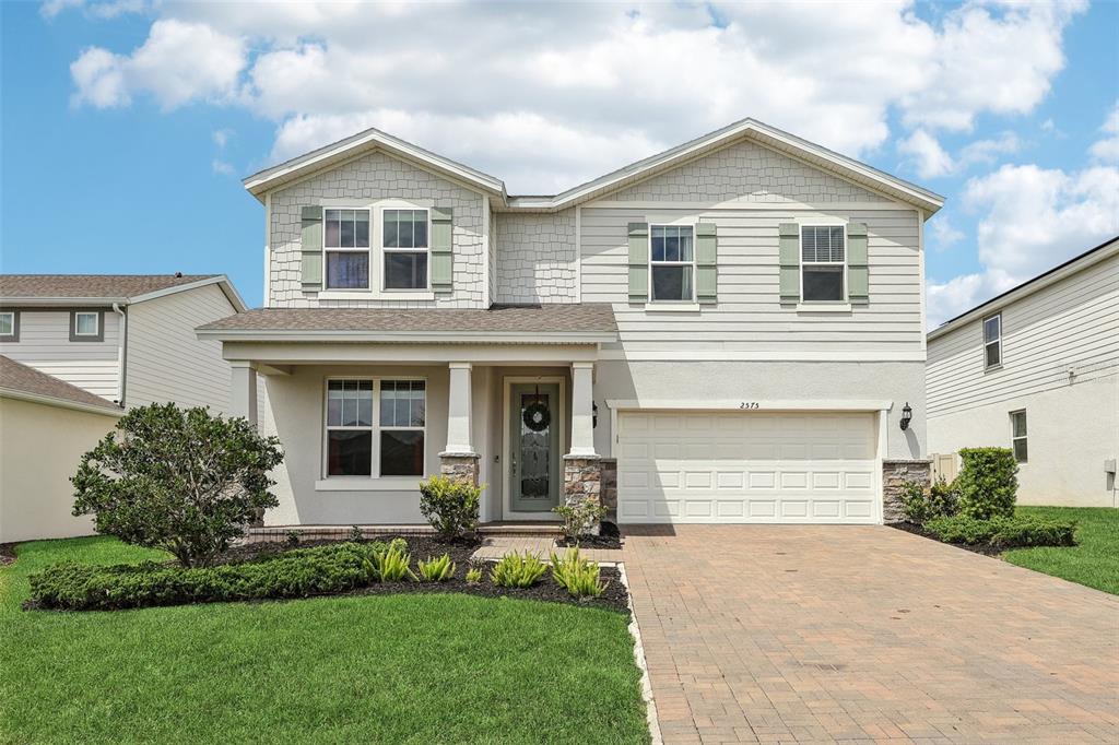 A two-story suburban house with a paved driveway, light siding, and a front porch — 2575 AUBURN RIDGE DRIVE, APOPKA, FL