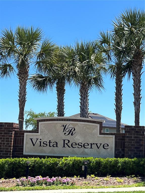A stone monument sign for Vista Reserve stands in front of palm trees and a house — 2575 AUBURN RIDGE DRIVE, APOPKA, FL