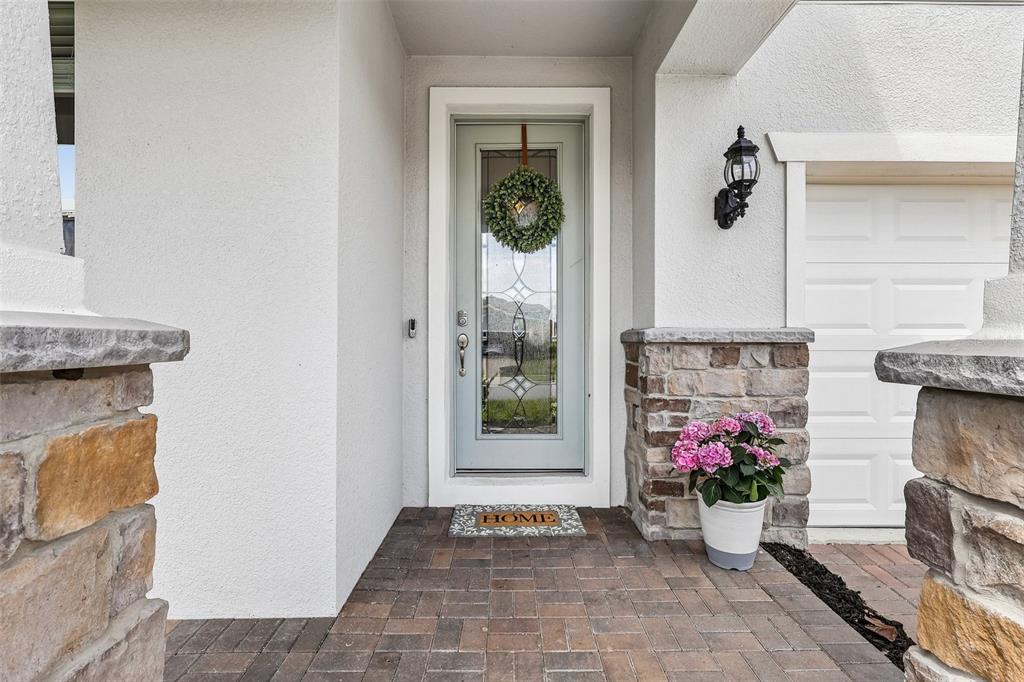 A front entryway features a light blue door with a wreath, stone accents, and pavers — 2575 AUBURN RIDGE DRIVE, APOPKA, FL