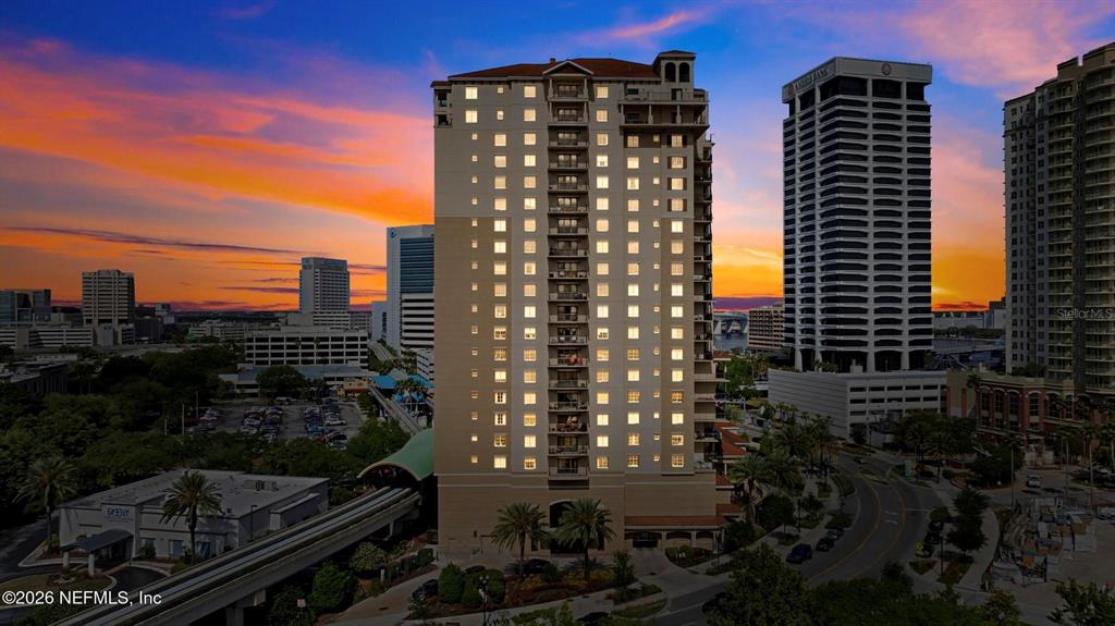 An aerial view shows a tall residential building at sunset with a monorail track nearby — 1478 RIVERPLACE BOULEVARD UNIT 1107, JACKSONVILLE, FL