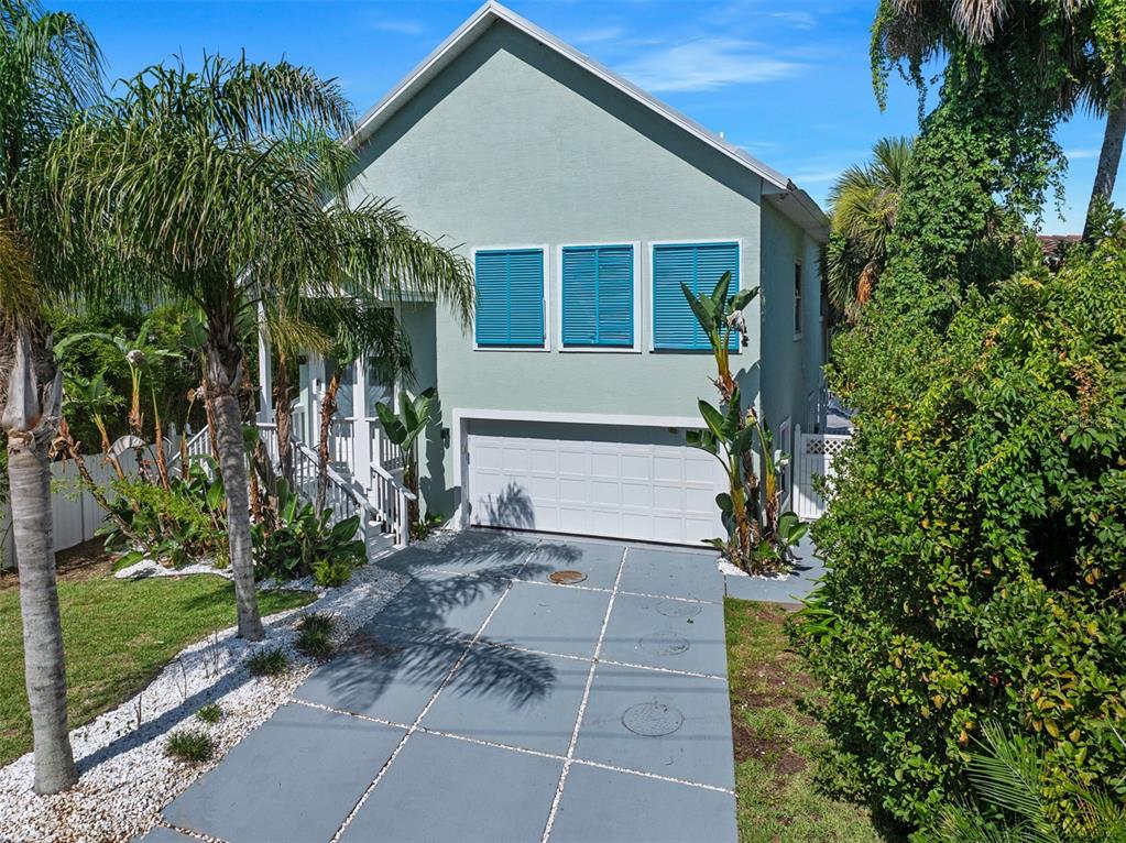 A light green two-story house features a white garage door and blue window shutters — 3110 JOHN ANDERSON DRIVE, ORMOND BEACH, FL