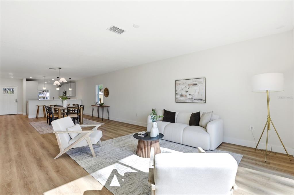 A bright open-concept living and dining area features light wood flooring and neutral furniture — 1336 MARSHALL DRIVE, LEESBURG, FL