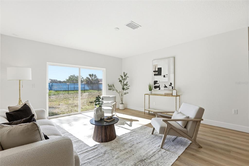A bright living room features a sofa, two armchairs, a coffee table, and a sliding door — 1336 MARSHALL DRIVE, LEESBURG, FL